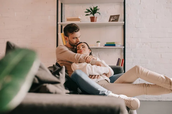 Attractive young couple embracing on couch at home — Stock Photo