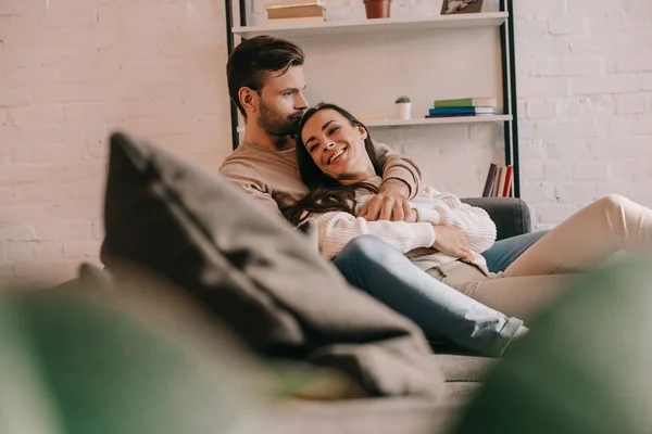 Attraktives junges Paar kuschelt zu Hause auf der Couch — Stockfoto