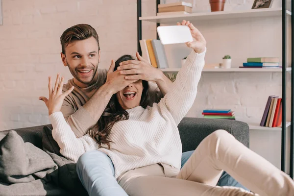 Feliz jovem casal tomando selfie com smartphone no sofá em casa — Fotografia de Stock