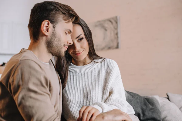 Jeune couple câlin sur canapé à la maison — Photo de stock