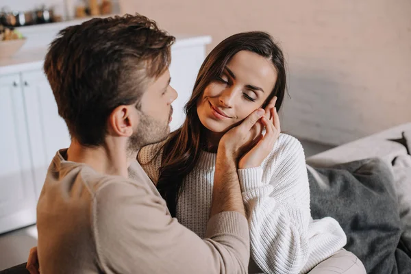 Sonriente tierna pareja abrazándose en sofá en casa - foto de stock