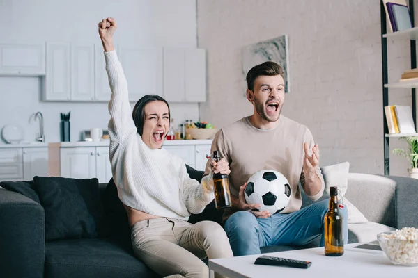 Ausdrucksstarkes junges Paar schaut Fußballspiel zu Hause und jubelt — Stockfoto