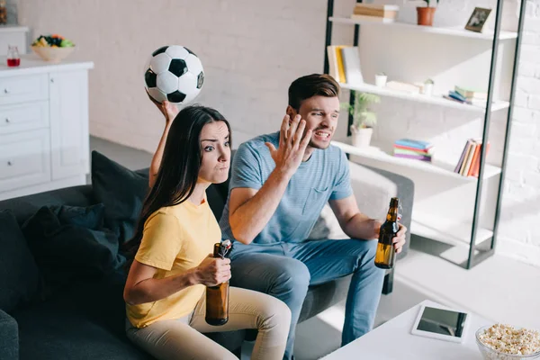 Expressivo casal jovem louco assistindo jogo de futebol em casa — Fotografia de Stock