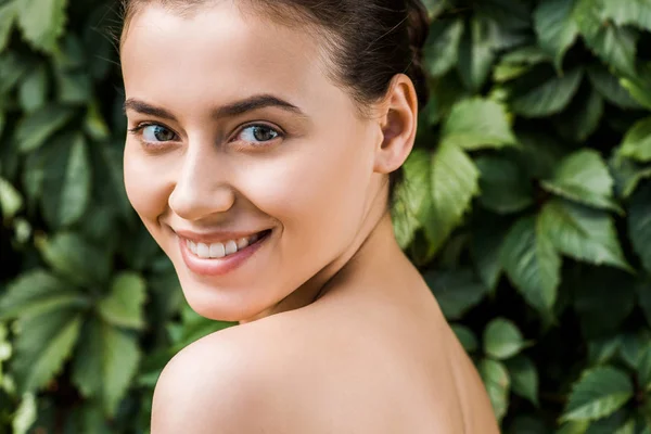 Sorridente giovane donna con foglie verdi sullo sfondo — Foto stock