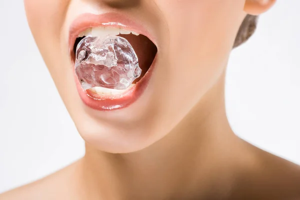 Mujer joven sosteniendo cubo de hielo en la boca aislado en blanco - foto de stock