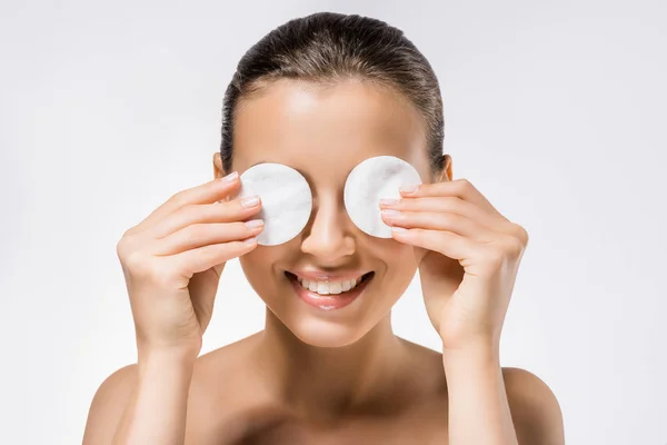 Jovem mulher sorridente segurando almofadas de algodão nos olhos — Fotografia de Stock