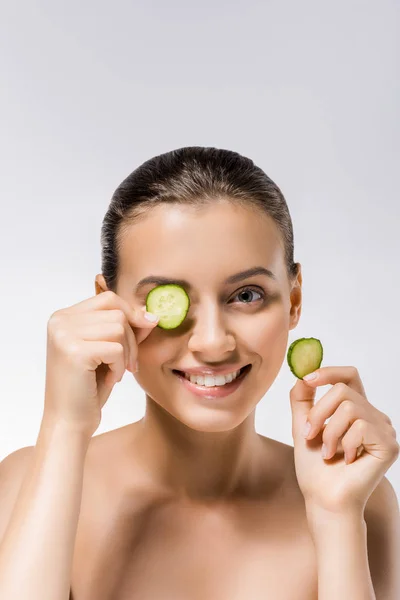 Young smiling woman with cucumber slice on eye — Stock Photo