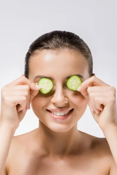 Jeune femme souriante avec des tranches de concombre sur les yeux — Photo de stock