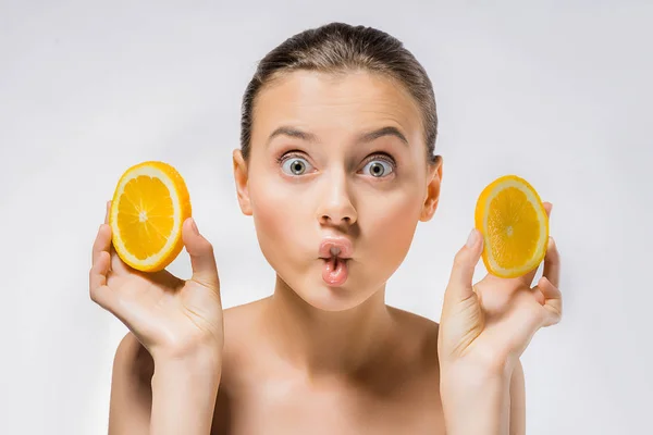 Mujer joven con expresión de la cara divertida y rodajas de naranja - foto de stock