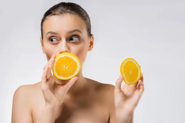 Jeune femme avec une expression drôle de visage et des tranches d'orange — Photo de stock