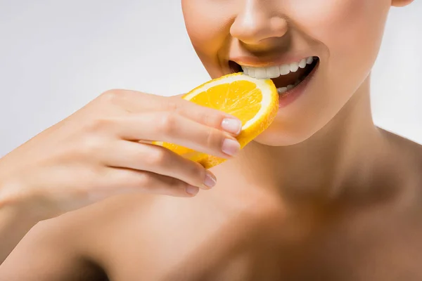 Young woman holding and biting orange slice — Stock Photo