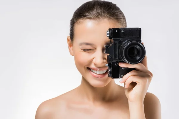 Mujer joven con el ojo cerrado ocultando la cara detrás de la cámara negra - foto de stock