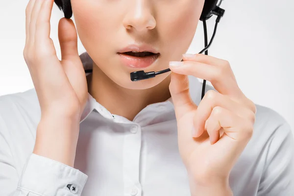 Close up of young call center operator touching headset and speaking in microphone — Stock Photo