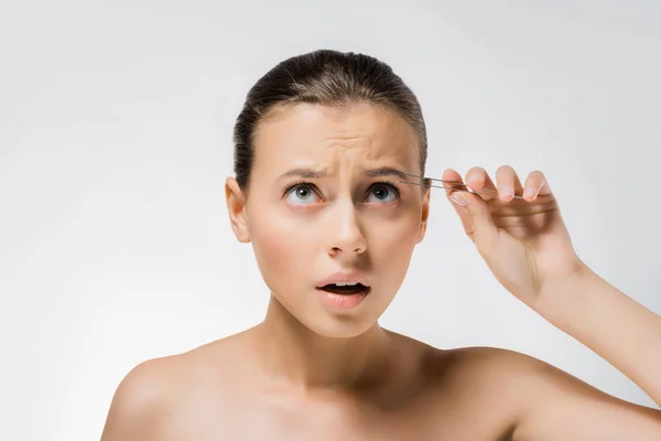 Young confused woman holding metal tweezers near face — Stock Photo