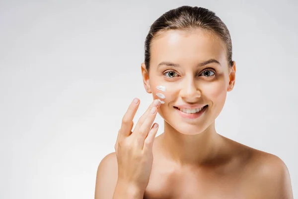Young beautiful woman applying white cream with fingers on cheek — Stock Photo