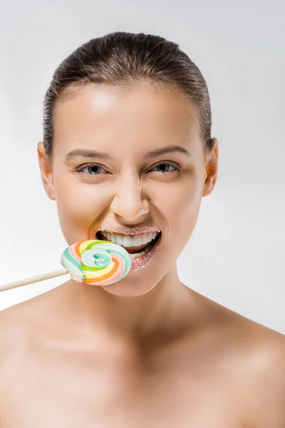 Jeune femme avec du sucre sur les lèvres mordant sucette colorée — Photo de stock