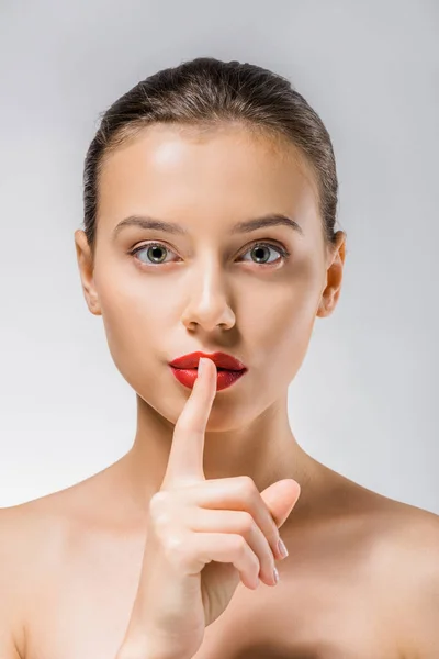 Jeune belle femme avec des lèvres rouges montrant symbole de silence — Photo de stock