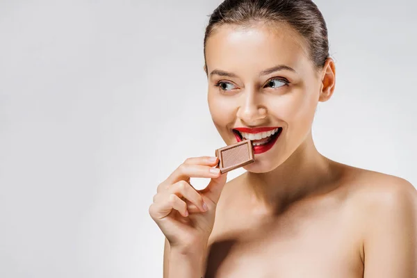 Jovem mulher bonita com lábios vermelhos mordendo pedaço de chocolate — Fotografia de Stock