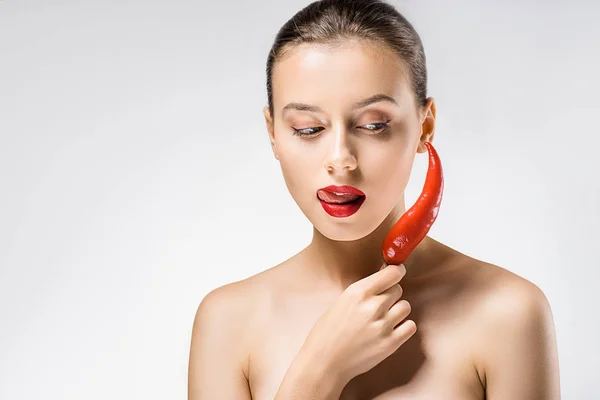 Young beautiful woman with red lips holding chili pepper and licking lips — Stock Photo