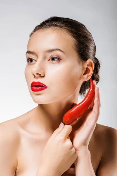 Young beautiful woman with red lips holding chili pepper near face — Stock Photo