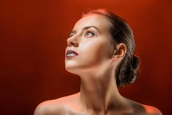 Joven hermosa mujer con labios brillantes sobre fondo borgoña - foto de stock