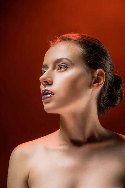 Young beautiful woman with shiny lips on burgundy background — Stock Photo