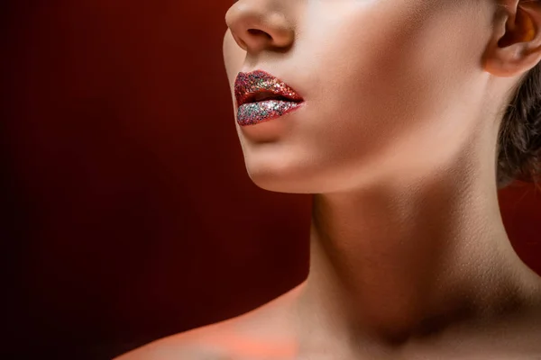 Close up of young woman with shiny lips on burgundy background — Stock Photo