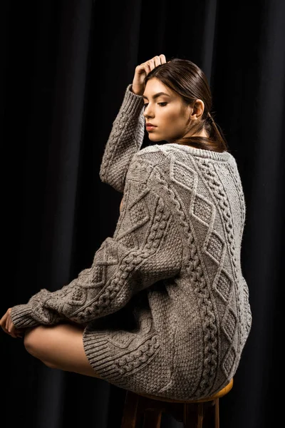 Attractive pensive woman in woolen grey sweater on black background — Stock Photo