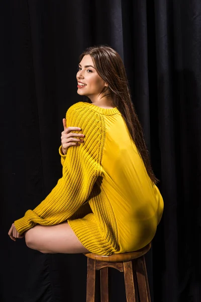Giovane donna sorridente in maglione di lana giallo su sfondo nero — Foto stock