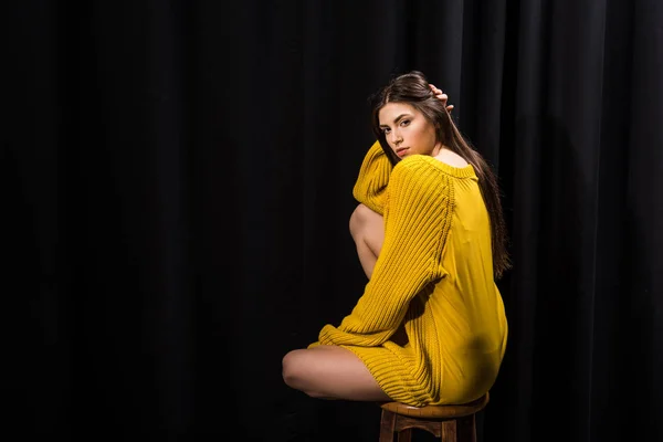 Young attractive woman in yellow woolen sweater on black backdrop — Stock Photo