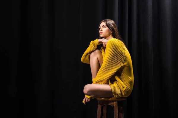 Side view of beautiful woman in yellow woolen sweater on black backdrop — Stock Photo