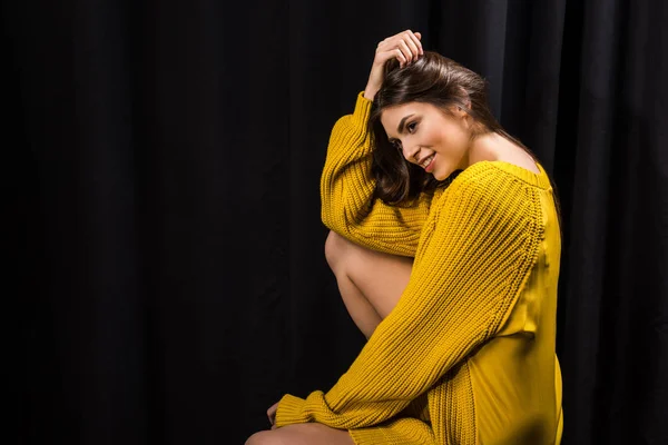 Side view of beautiful woman in yellow woolen sweater on black backdrop — Stock Photo