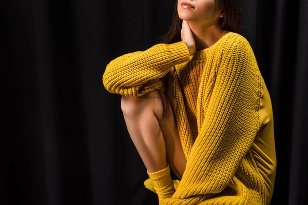 Tiro recortado de mujer en suéter de lana amarillo sobre fondo negro - foto de stock