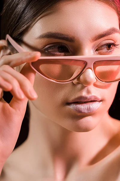 Retrato de belo modelo em óculos na moda olhando para longe isolado em preto — Fotografia de Stock