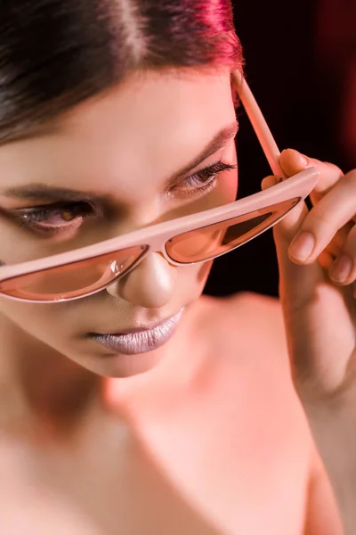 Retrato de modelo elegante en gafas posando sobre fondo oscuro - foto de stock