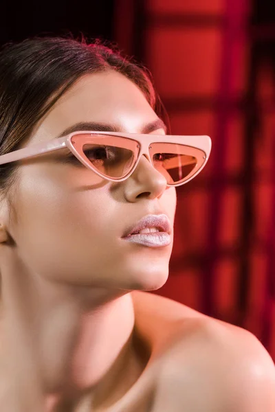 Retrato de modelo elegante en gafas posando sobre fondo oscuro - foto de stock