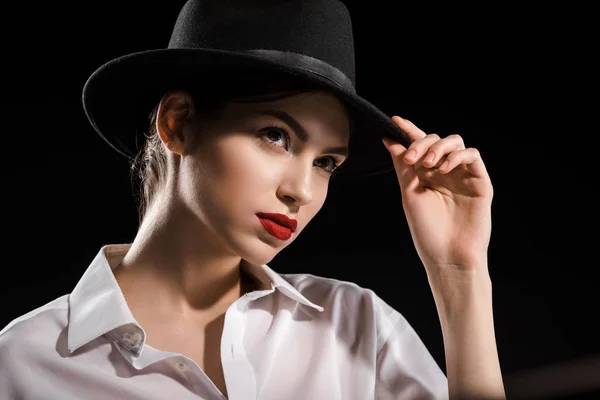 Retrato de mulher bonita em camisa branca e chapéu preto posando isolado em preto — Fotografia de Stock