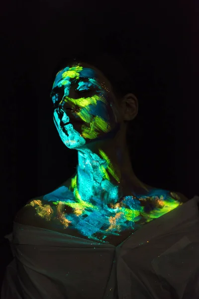 Woman with ultraviolet paints on face posing on black background — Stock Photo