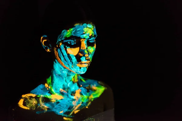 Model with colorful neon paints on body posing on black backdrop — Stock Photo