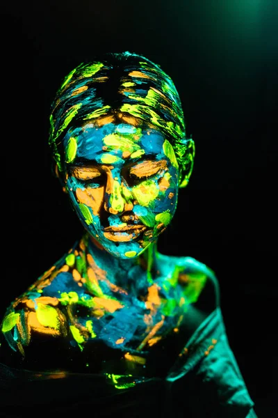 Portrait of woman painted with bright neon paints on black backdrop — Stock Photo