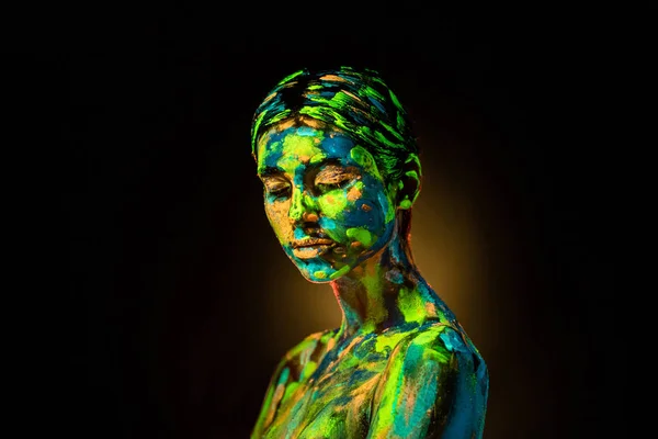 Portrait of beautiful woman with colorful ultraviolet paints on body on black backdrop — Stock Photo