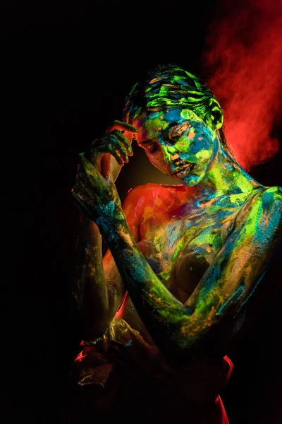 Portrait of beautiful woman with colorful ultraviolet paints on body on black backdrop — Stock Photo