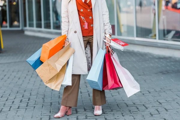 Vista recortada de hembra adicta a las compras con bolsas de compras y signo de descuento - foto de stock