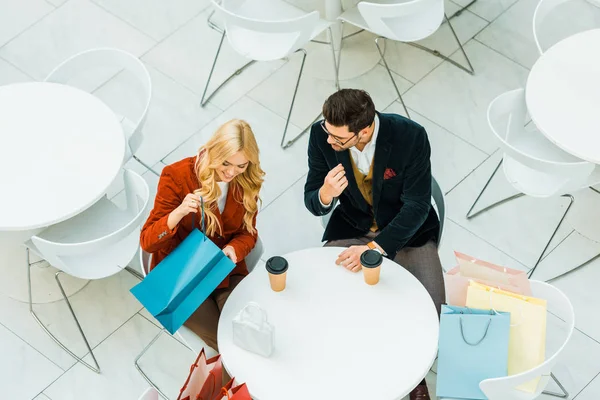 Vista aérea de belo casal elegante com sacos de compras sentado no café — Fotografia de Stock