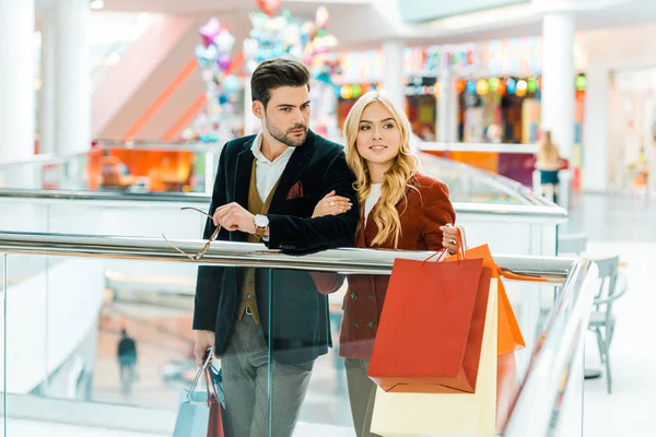 Jovem casal com sacos de compras passar tempo no centro comercial — Fotografia de Stock
