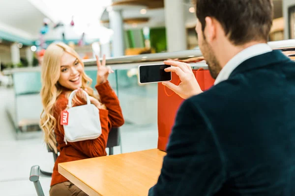 Man taking photo of happy beautiful girlfriend holding bag with sale tag — Stock Photo