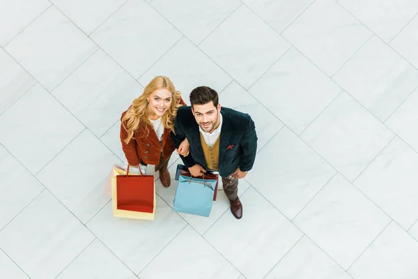 Vista aérea de hermosa pareja feliz sosteniendo bolsas de compras - foto de stock