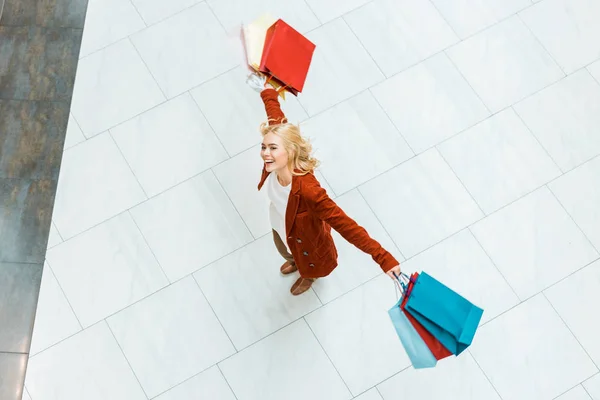 Overhead view of attractive happy girl with colorful shopping bags — Stock Photo