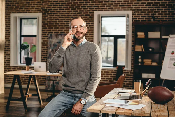 Homme d'affaires occasionnel parlant sur smartphone dans le bureau loft — Photo de stock