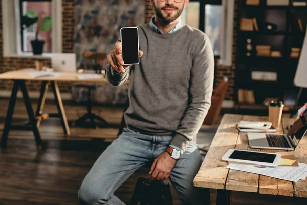 Vista recortada de empresario casual sosteniendo teléfono inteligente con pantalla en blanco en la oficina loft - foto de stock